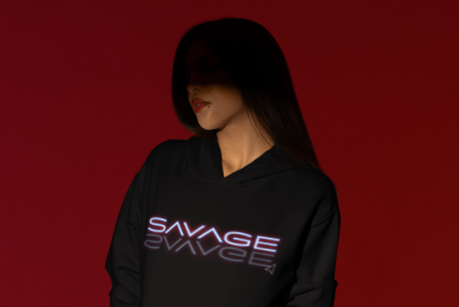 SAVAGE black logo hoodie modeled against a red background